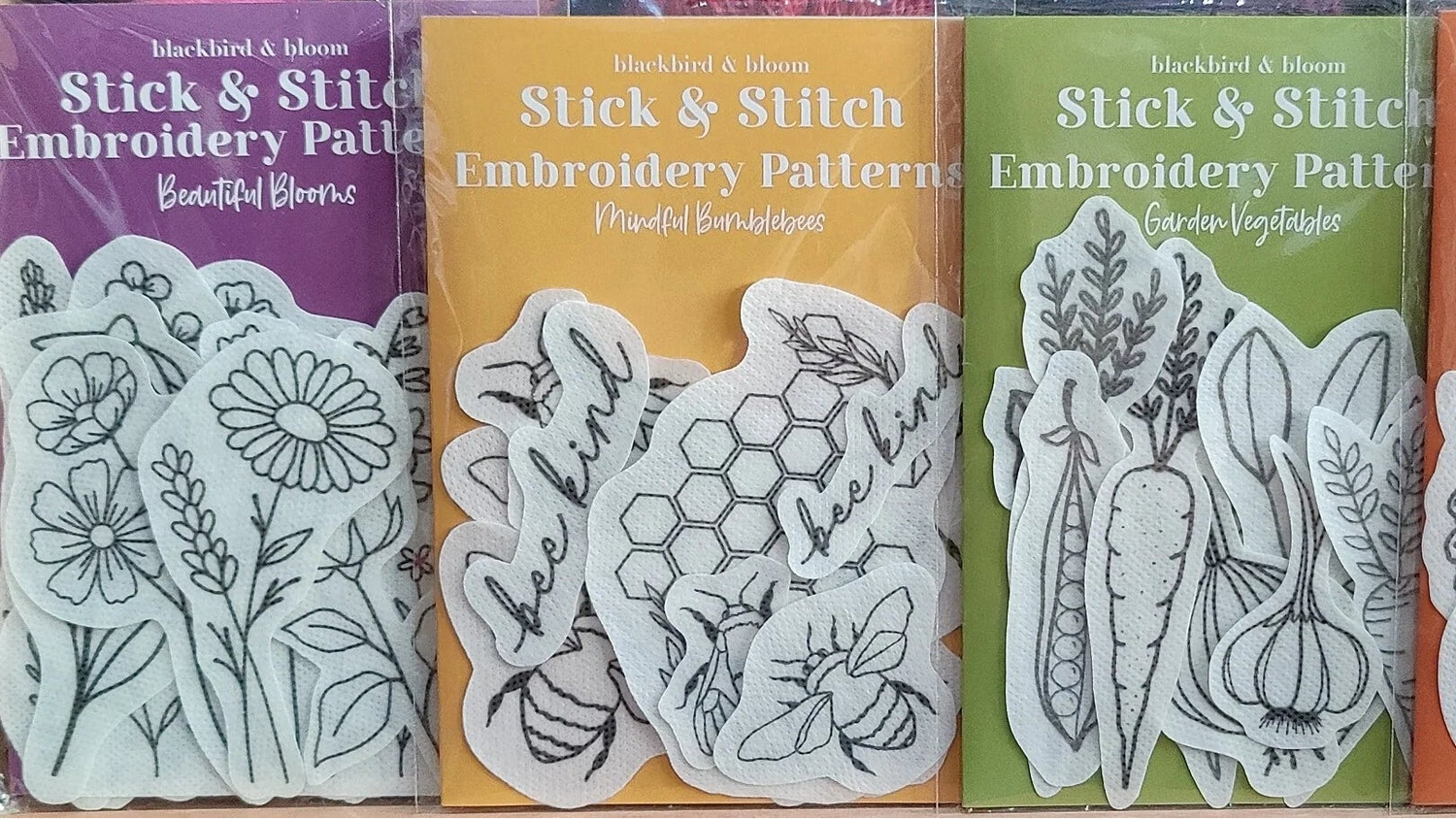Yarn skeins with 'Stick & Stitch' embroidery pattern books on a wooden shelf.