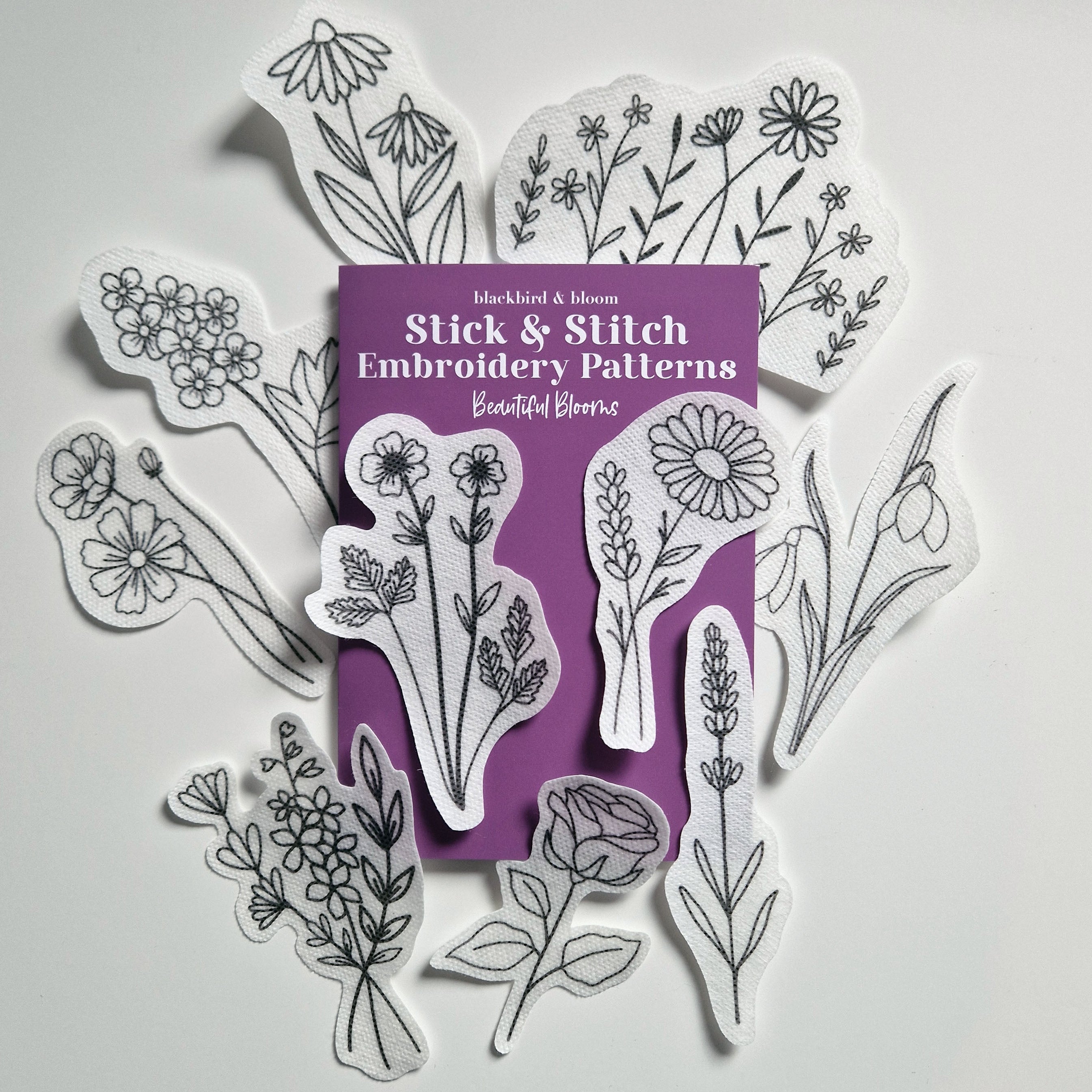 A collection of floral embroidery patterns in various sizes designed for stick and stitch embroidery, displayed on a white background with a purple packaging in the center.