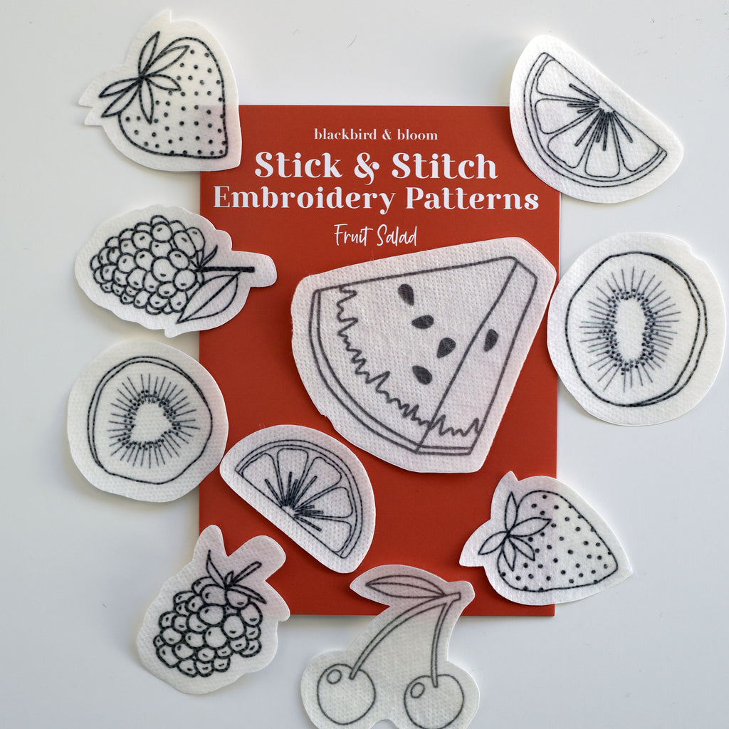 Various embroidery patterns of fruit salad designs scattered around an orange guide card with the title 'Stick & Stitch Embroidery Patterns' by Blackbird & Bloom.